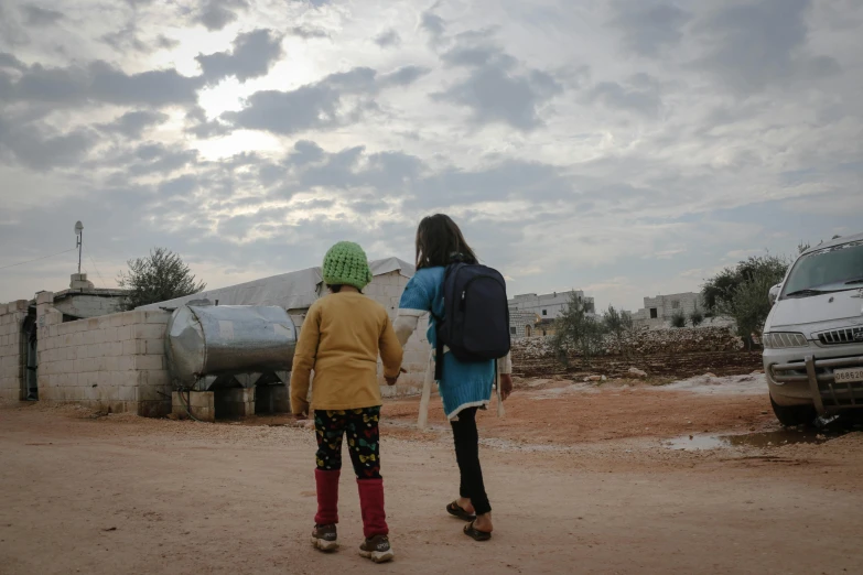 two children standing in the dirt near an suv