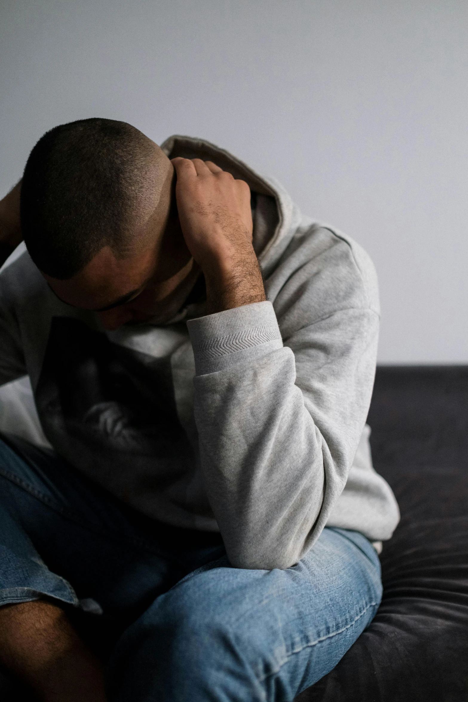 a man sitting on top of a couch holding his head