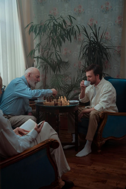 three older men play chess while a younger woman holds her hand