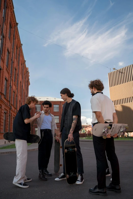 four guys are standing in the street with skateboards