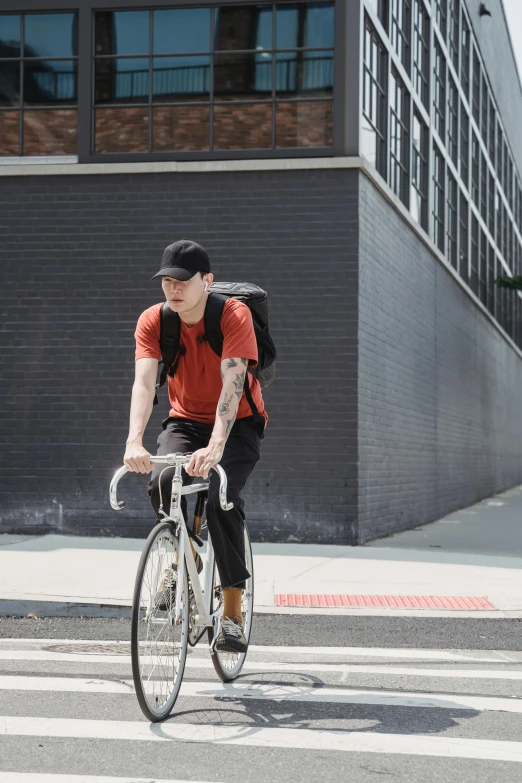 a man with tattoos riding a bicycle across the street