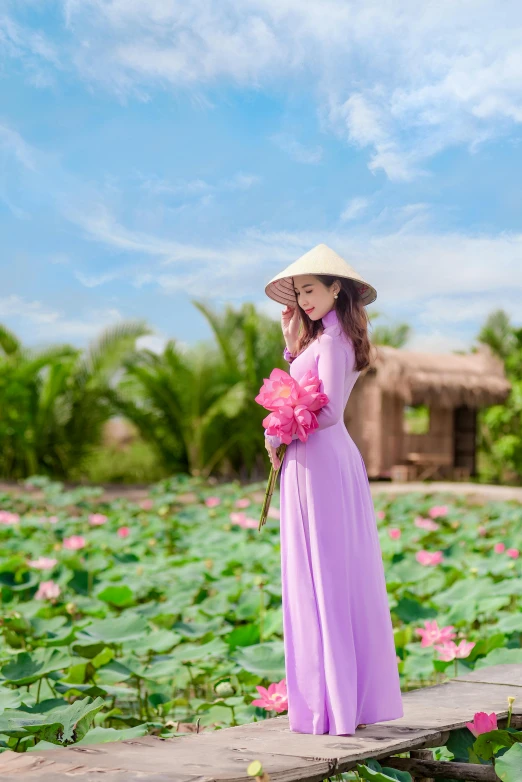 a girl is standing on a platform in a field with lotuses