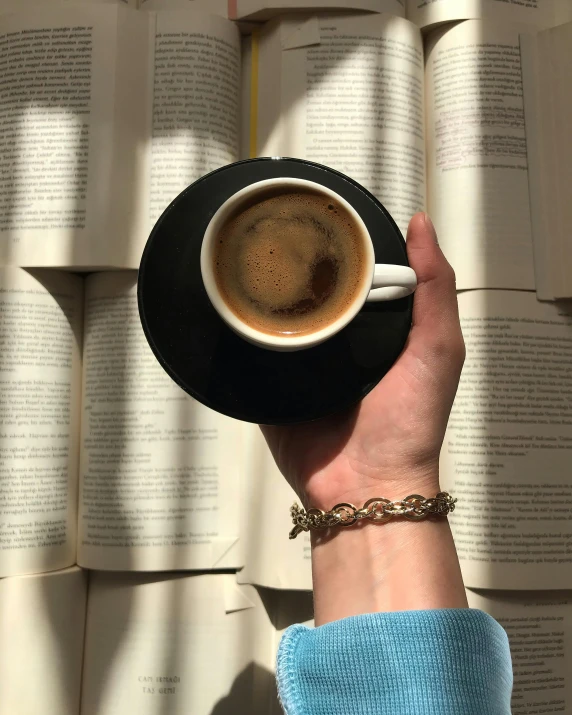 a person holds an open book and cups of coffee