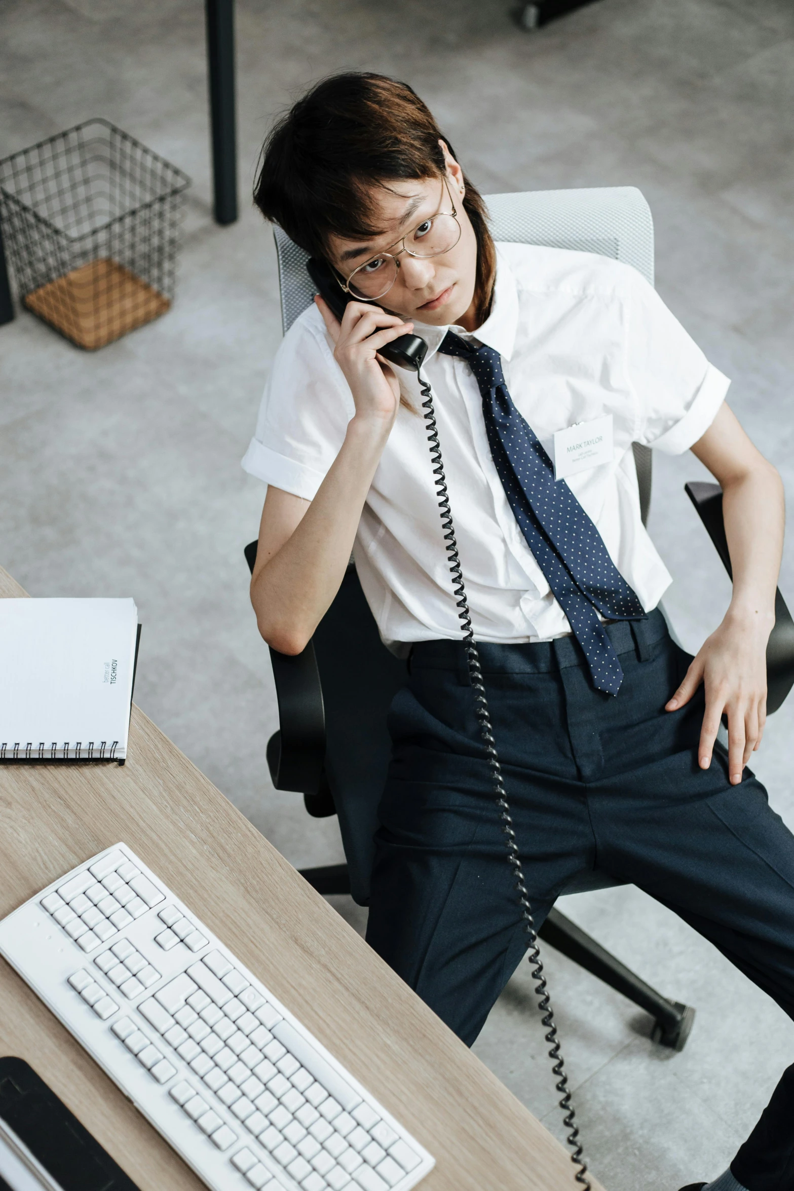 a man sitting in front of a computer holding a telephone to his ear