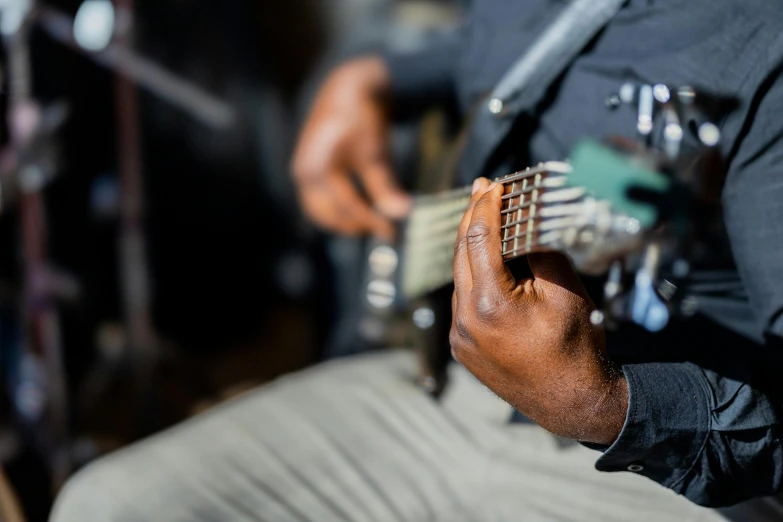 the hands of an african american male playing an acoustic guitar