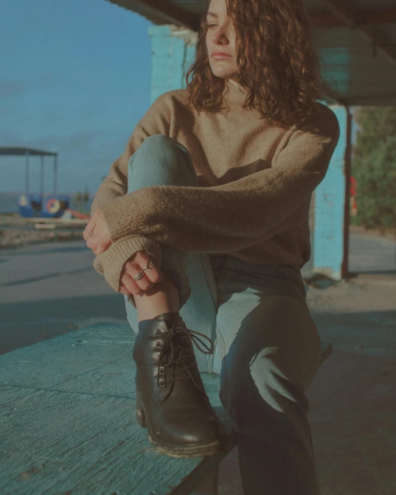 a  sitting with her feet up on a wooden bench