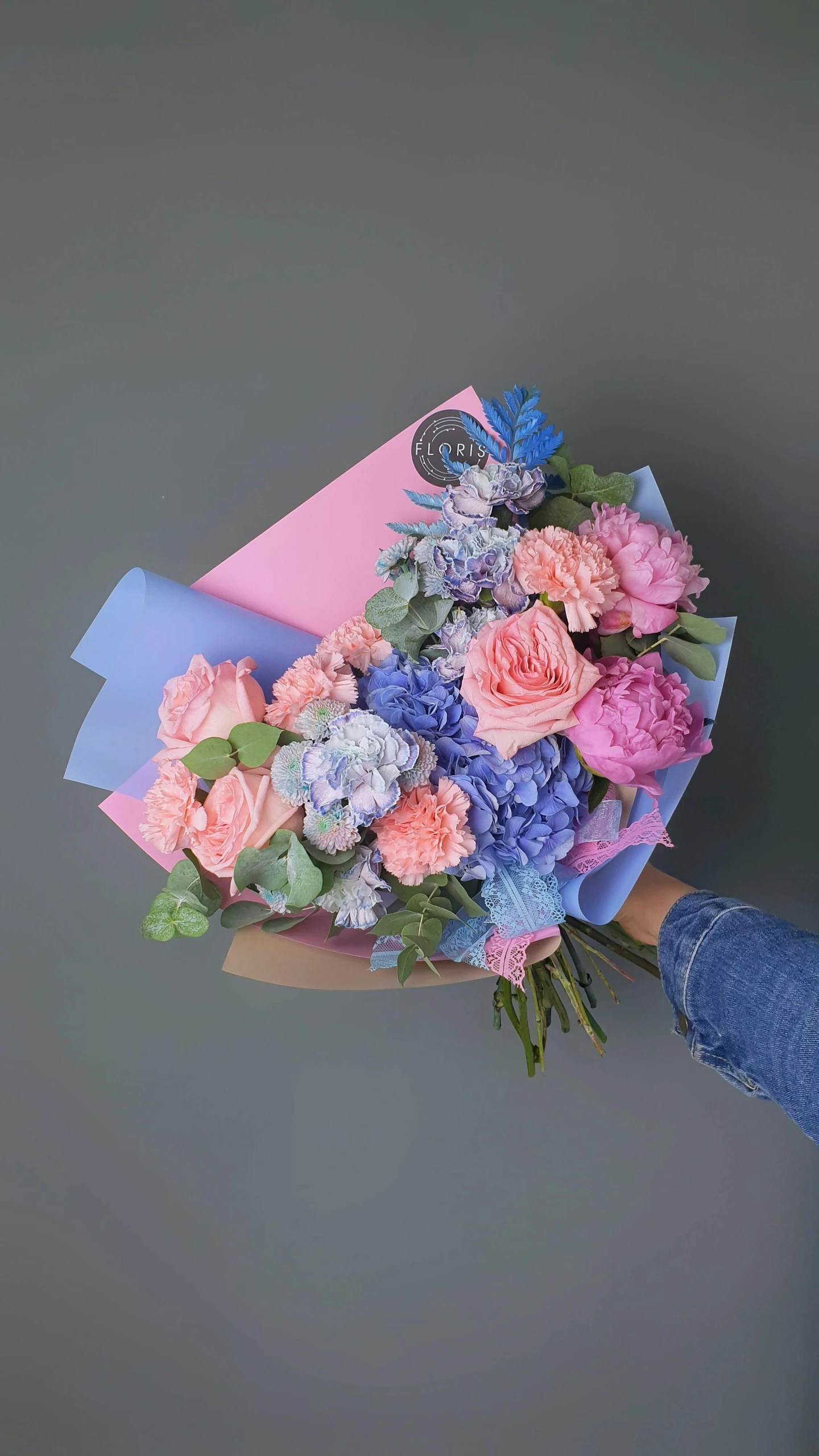 a person holds a bouquet of pink, blue, and purple flowers