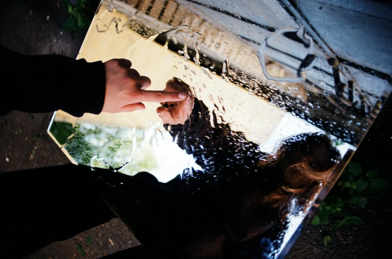 a hand holds soing while standing in front of a water fountain