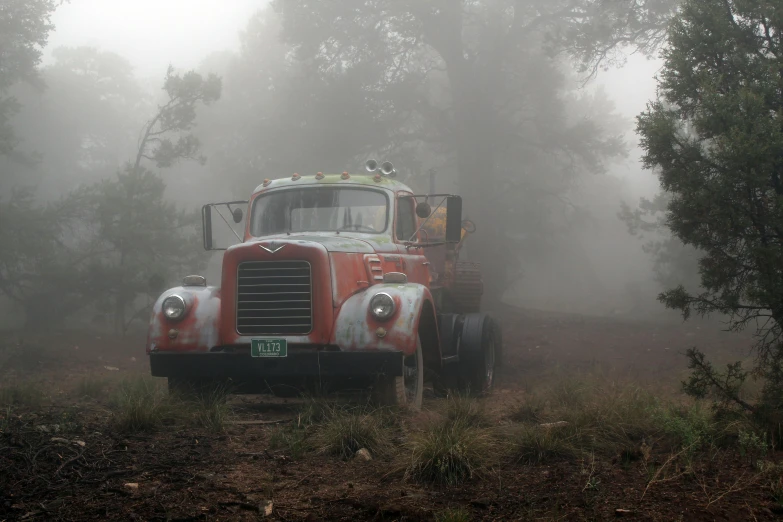 an old truck is parked on a foggy day