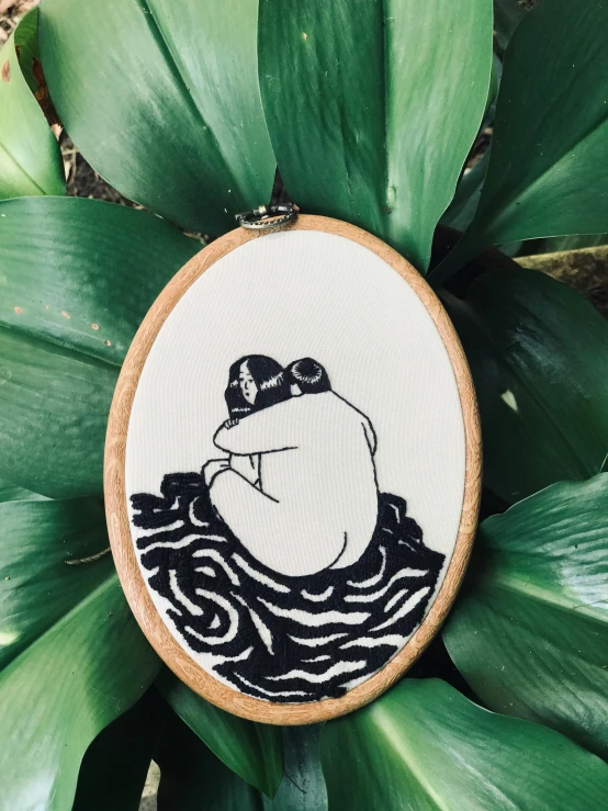 a black and white embroideryed cartoon of a frog on top of water