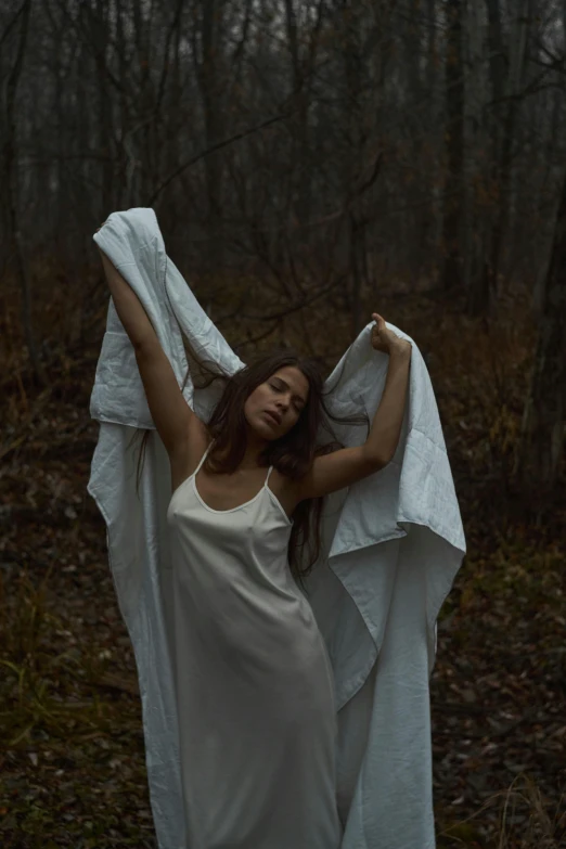 a woman in a white dress and her arms are spread over her head