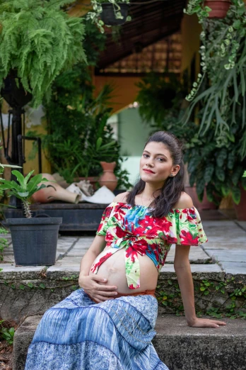 a beautiful young pregnant woman sitting in a garden