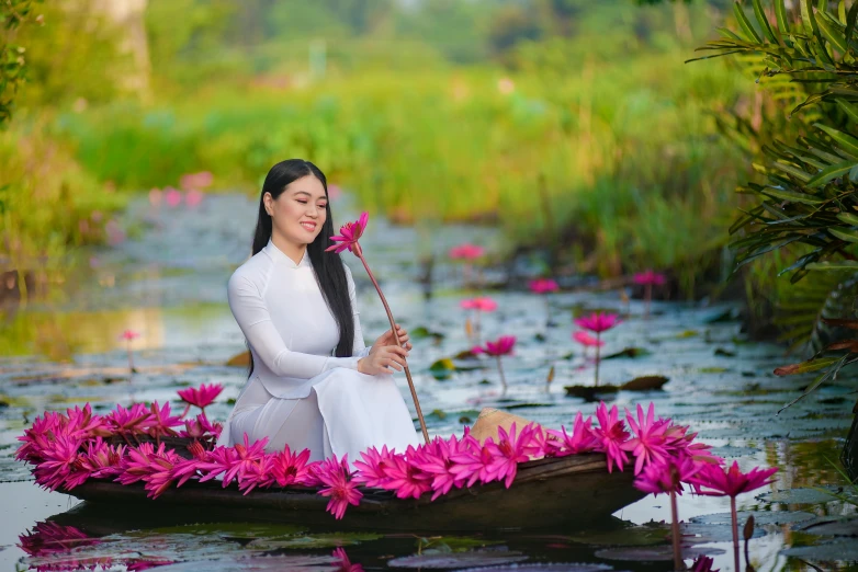 a woman in white sitting in a boat on pink flowers