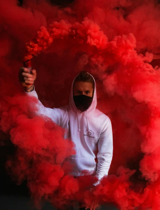a guy in white holding onto a red smoke bomb