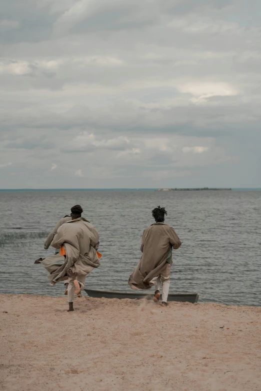 two people are walking toward the water on a beach