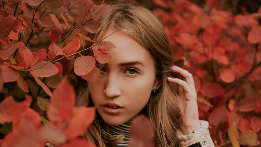 a woman is posing for a po in front of leaves