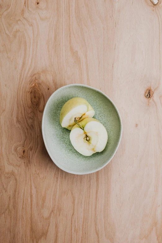 a green plate has two pieces of apple in it