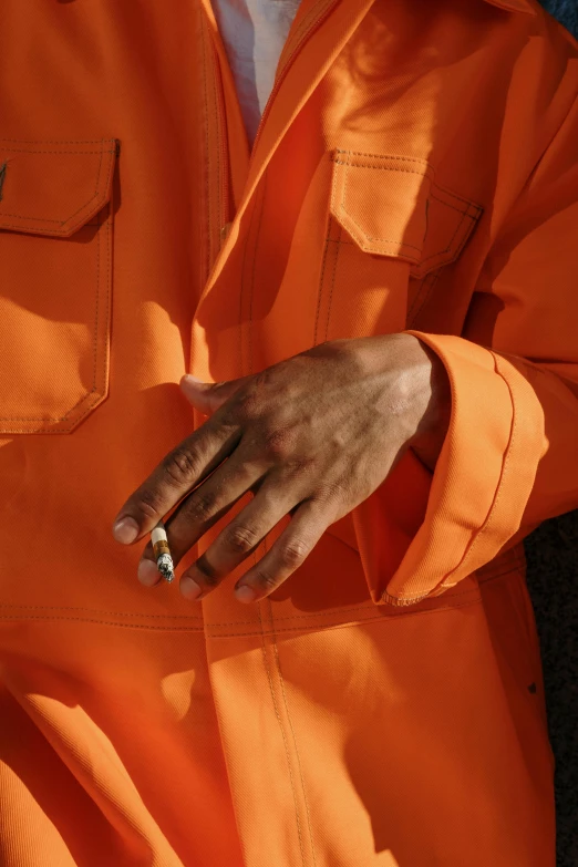 an orange suit has a small diamond ring on his hand