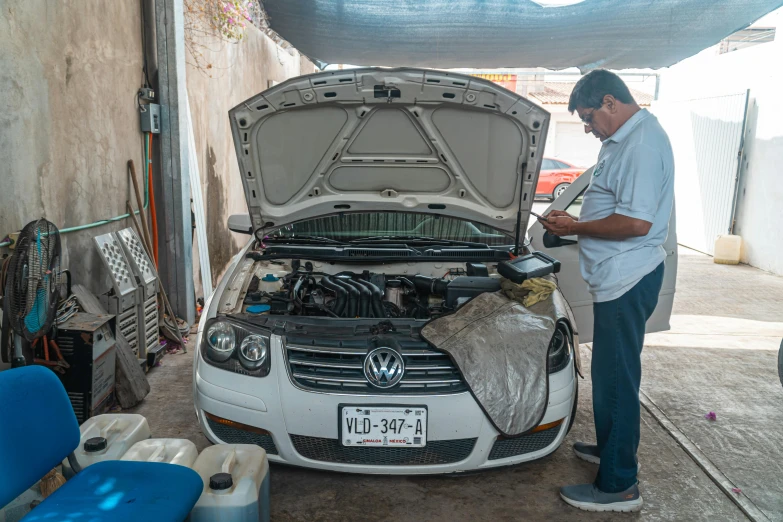 the man works on the engine of the small car