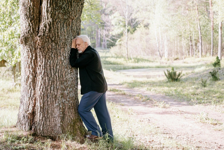 a man leaning against a tree in a forest