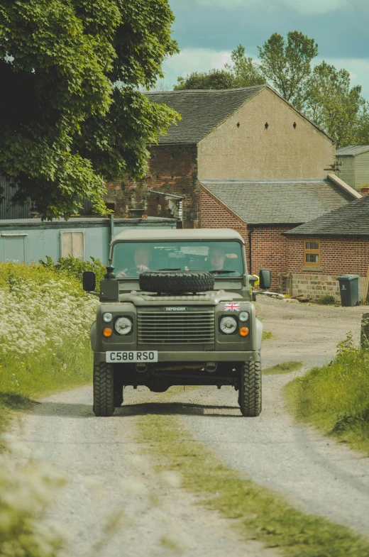 a green jeep drives down a country road