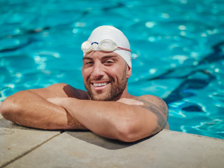 a man with his arms crossed in the pool, smiling