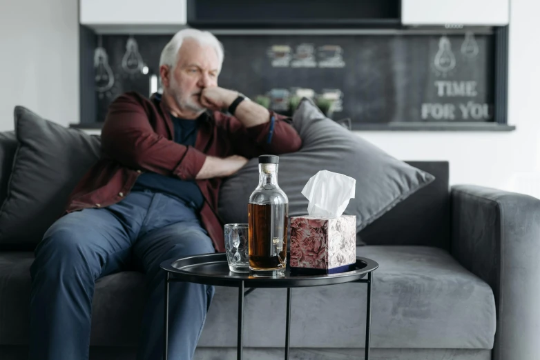 a man sitting on a couch drinking a beverage and liquor