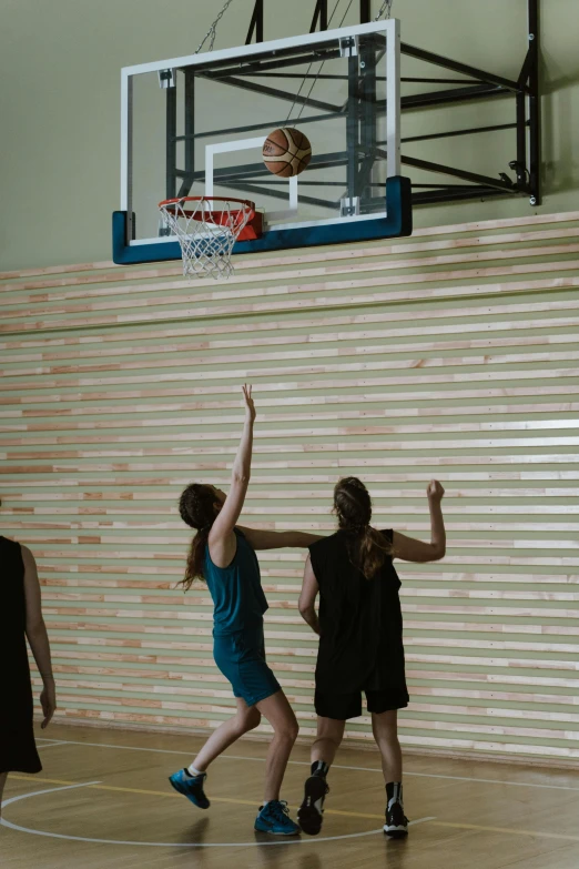 girls in blue are jumping for a basketball