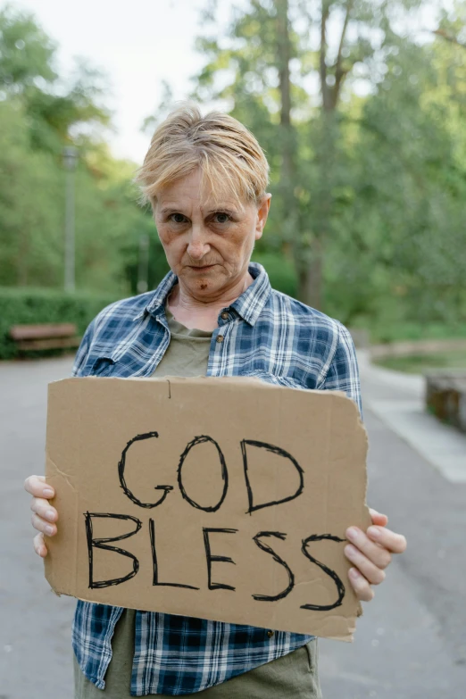 a woman holding a cardboard sign that says god bless