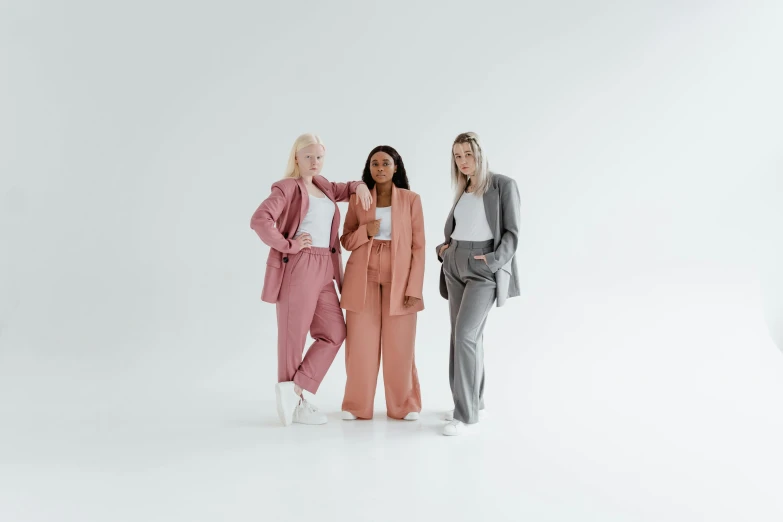 three women in bright pink and grey outfits standing in front of a white background