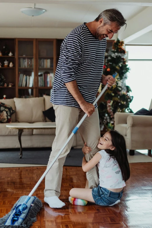 a little girl and a man with mop standing on the floor