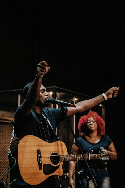 a man holding an acoustic guitar on top of a stage