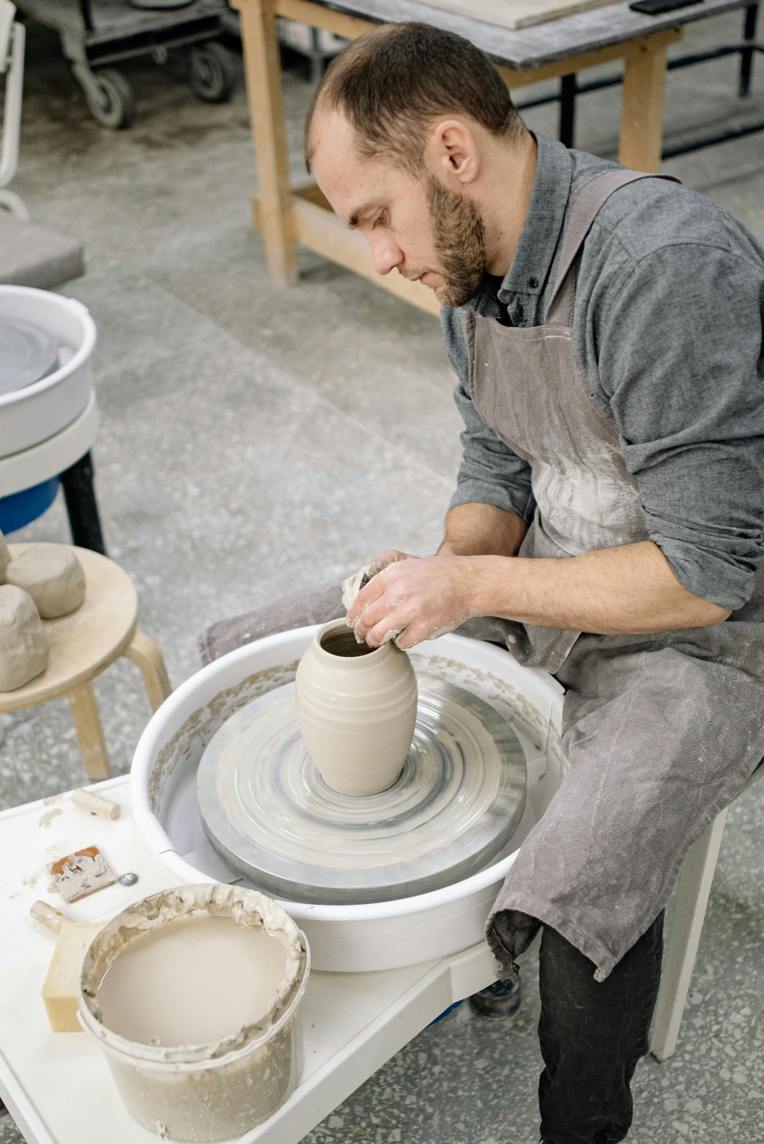 a man that is sitting on a table making a pot