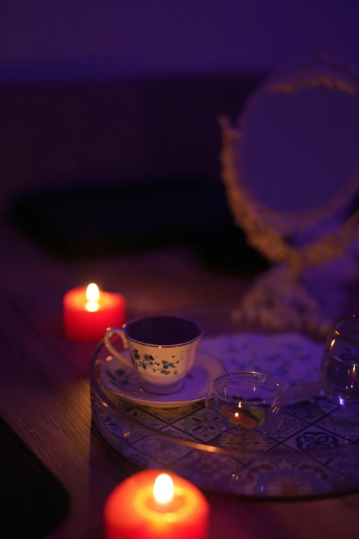 two teacups sitting on a table surrounded by candles