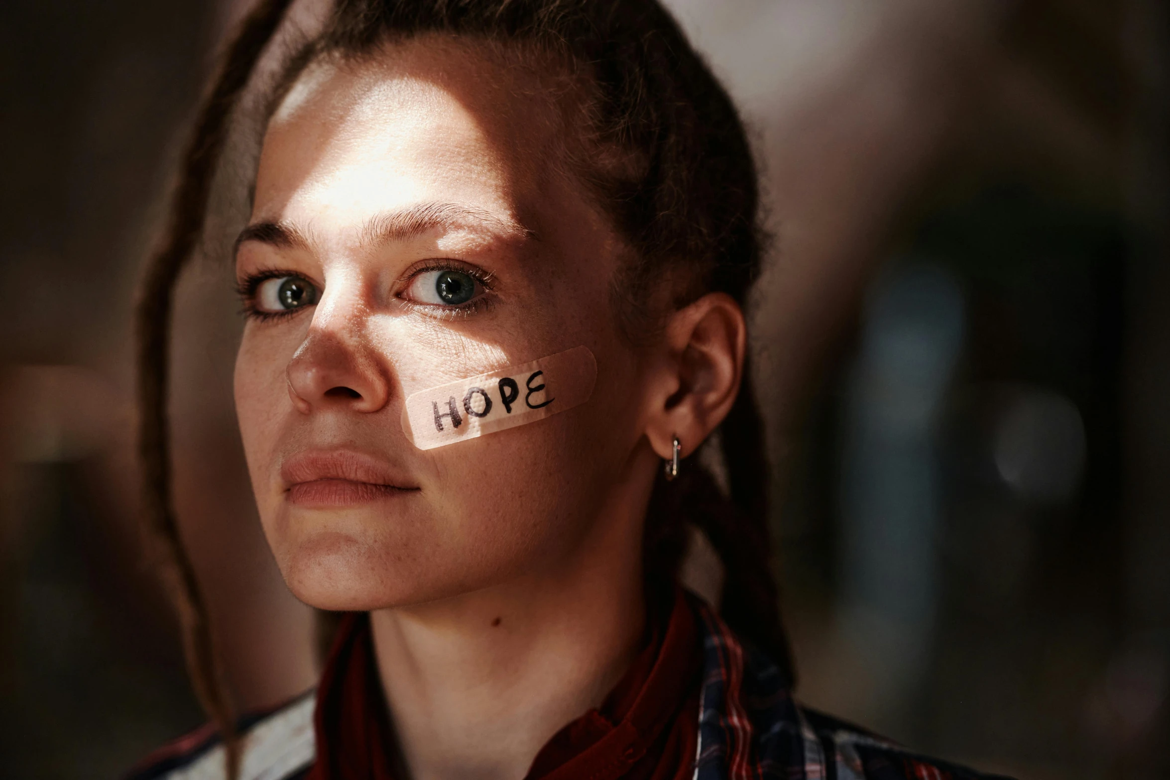 a woman with a tape on her cheek has the word hope painted in it