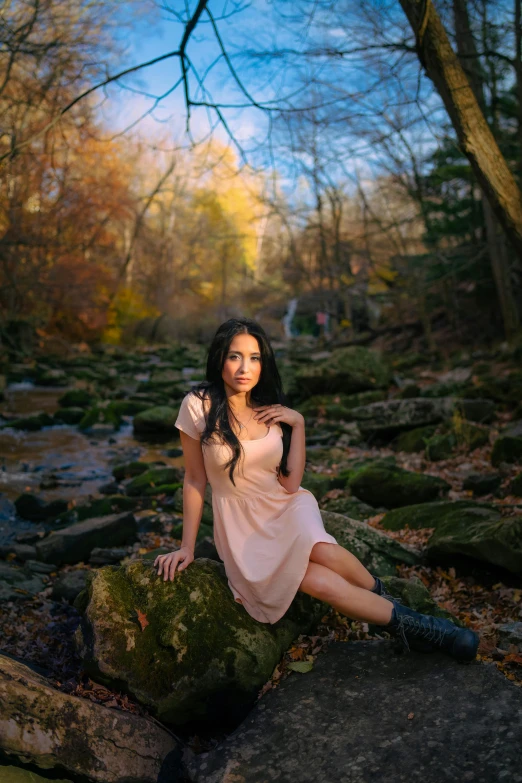 a woman in a dress posing on rocks and looking at the camera