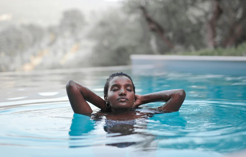 a young woman laying on the water in a pool