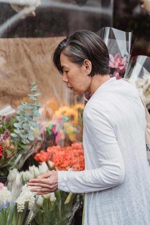 a woman looks at the flowers that are being sold for