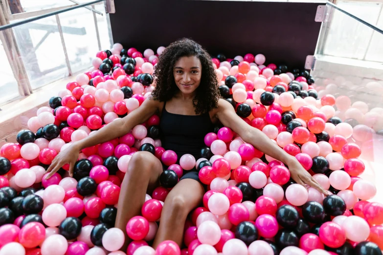 a young lady is sitting in the middle of a ball pit
