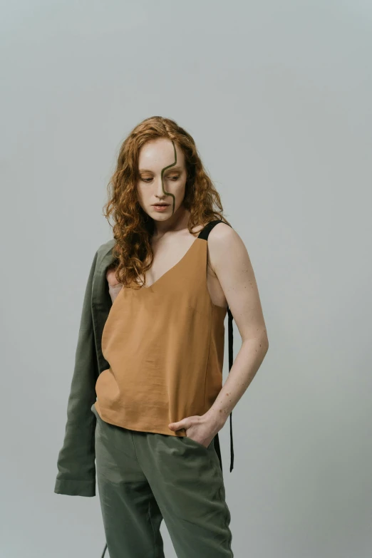 a woman in an orange top is posed with her hands behind her back