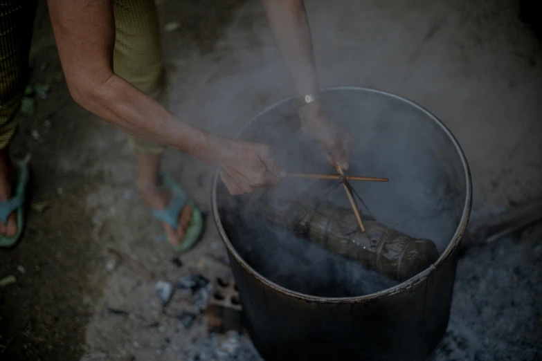 someone standing over a smokey cooking pot