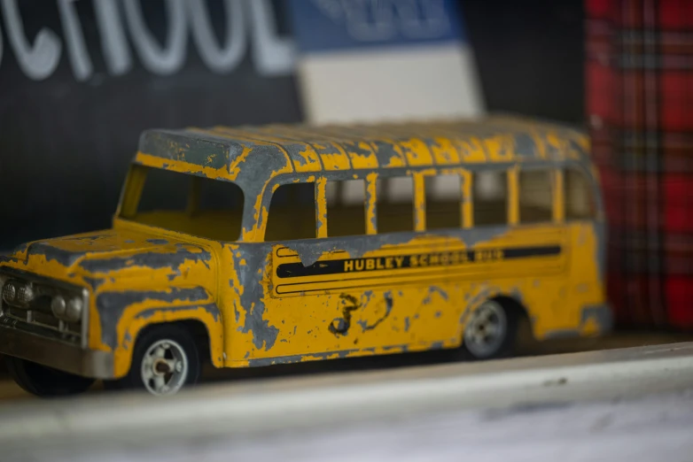 an old yellow toy bus sitting next to a sign