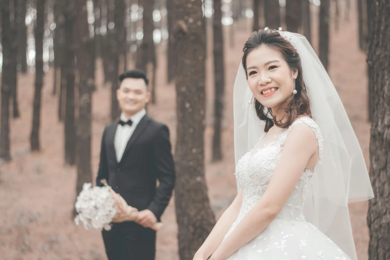 a bride and groom in a wooded area are taking portraits