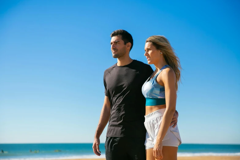 a man and woman walking on the beach