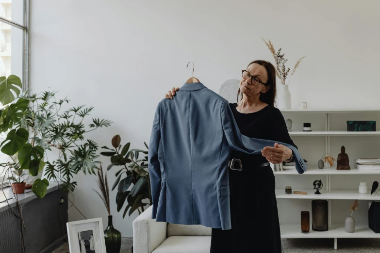 an older woman standing in her living room with a blue shirt