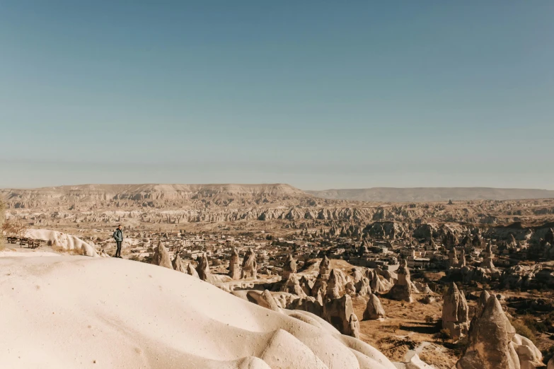 man with red backpack standing on rock formation overlooking landscape