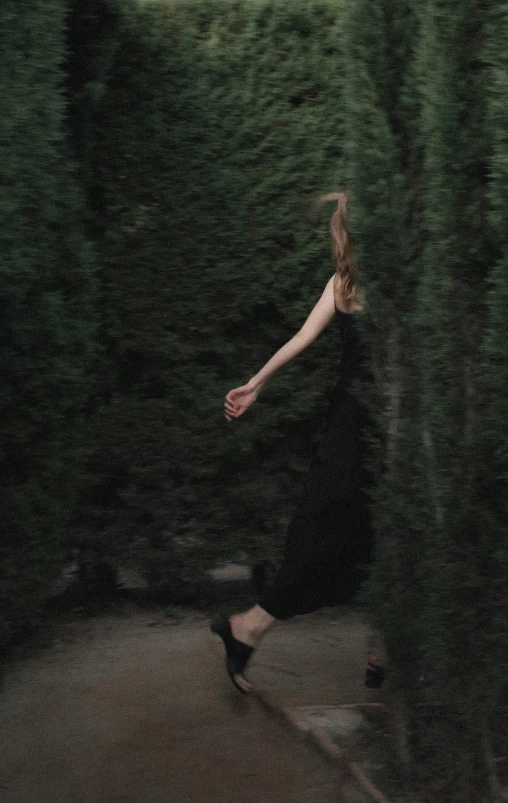 a woman walking through a forest like area