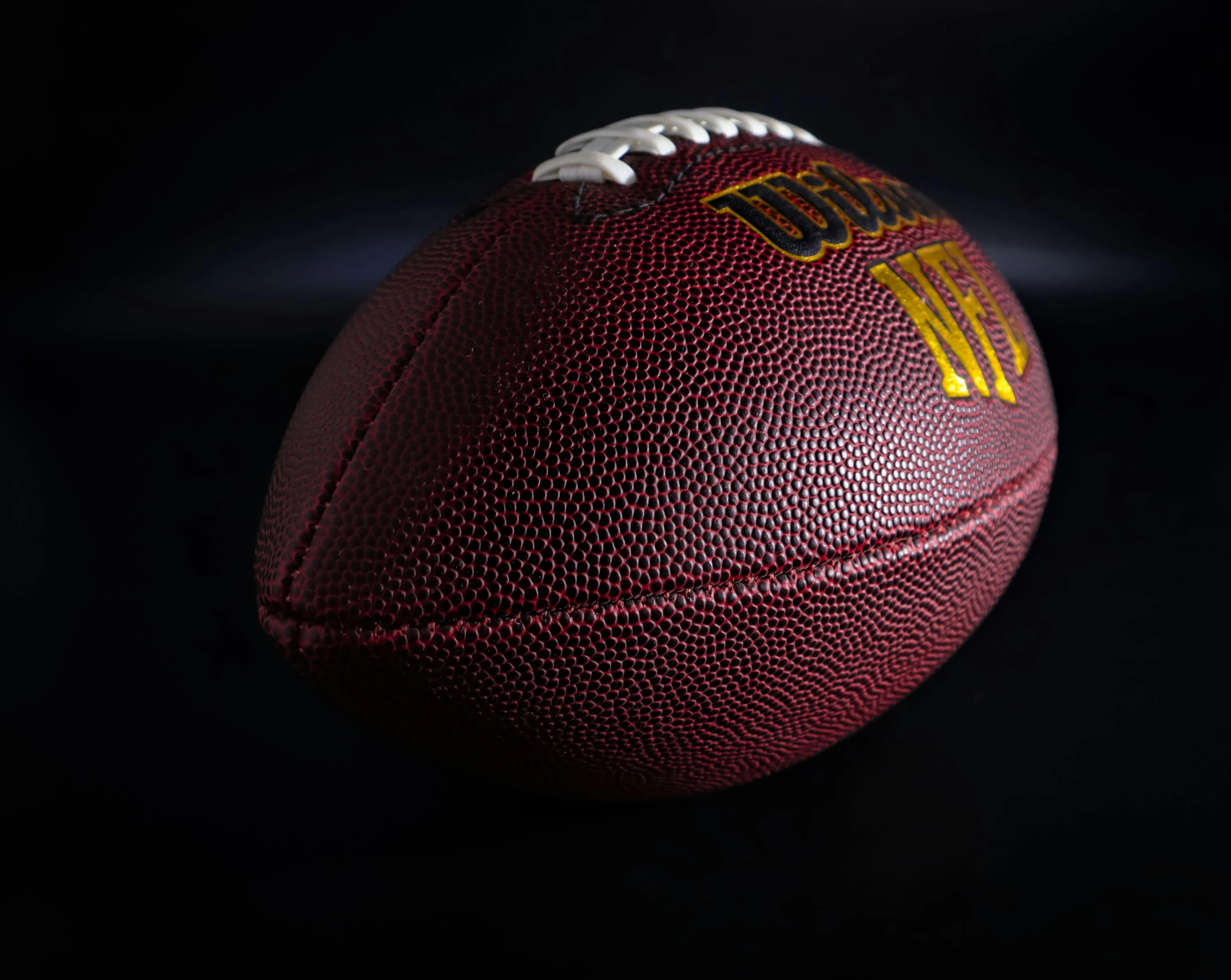 a close up view of an american football on a black background