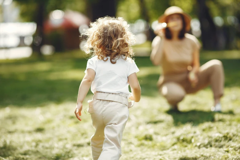 a child walks down the grass in front of an older person