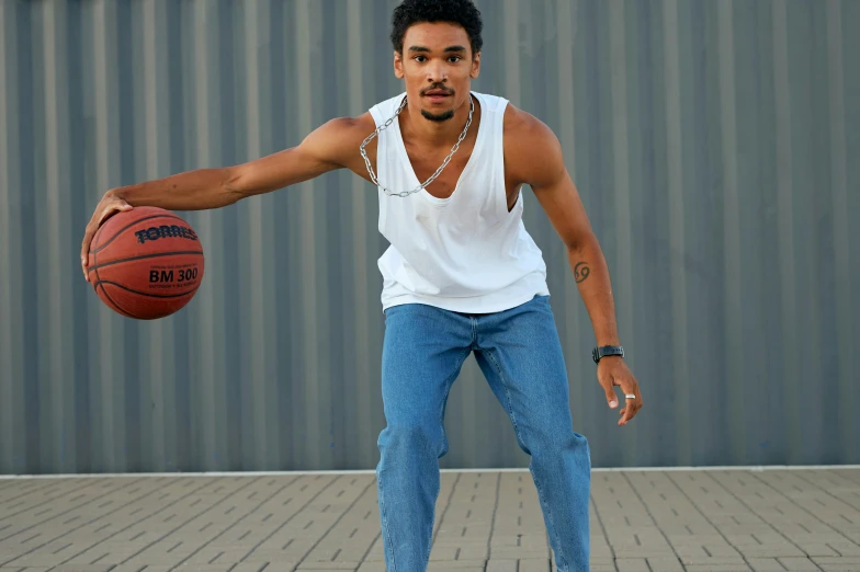 young man dribbling basketball on brick walkway near building